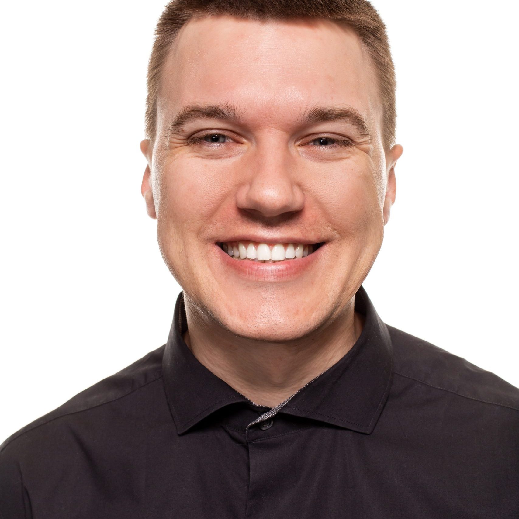 Handsome young man in a black shirt is smiling at the camera and looking happy, while standing isolated on a white background